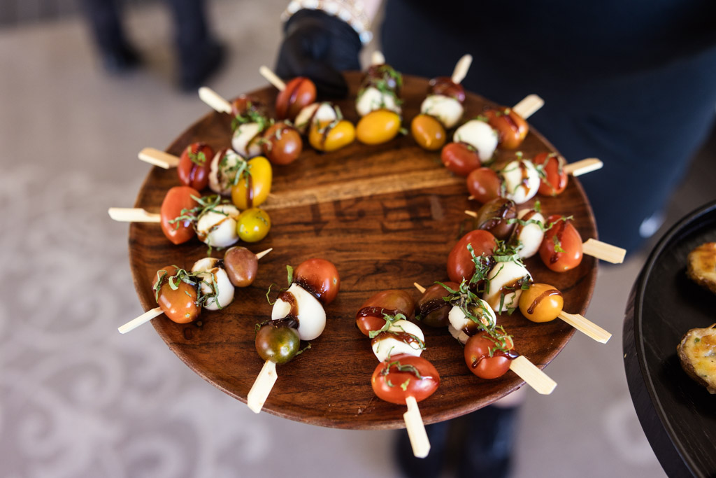A wooden tray from Être Farms with skewers of cherry tomatoes, mozzarella, and basil arranged in a circle