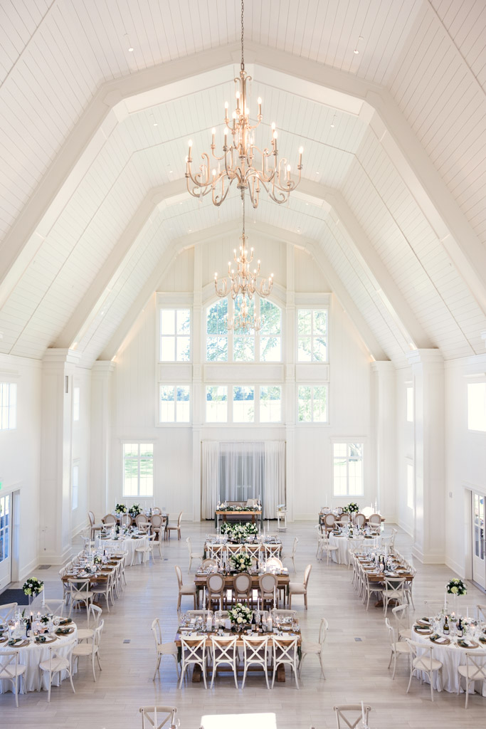 Bright wedding reception hall at Être Farms with high ceilings, chandeliers, and decorated tables