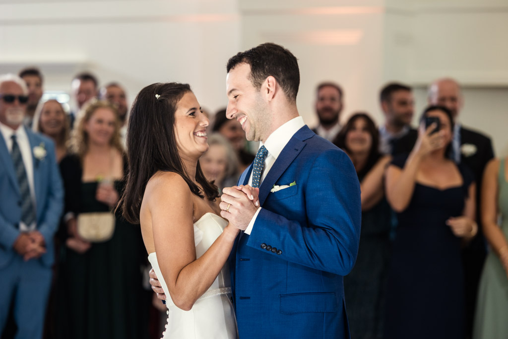 Bride and groom share their first dance, smiling at each other, surrounded by guests at their Être Farms wedding reception