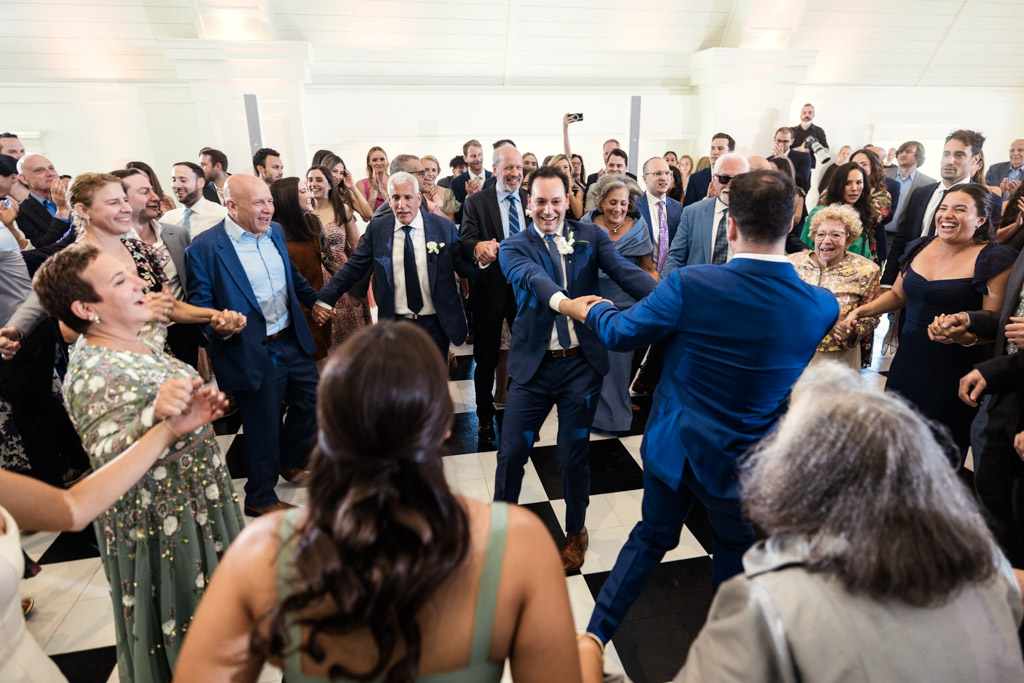 Groom and his brother dance at the center of a joyful crowd at Être Farms wedding reception