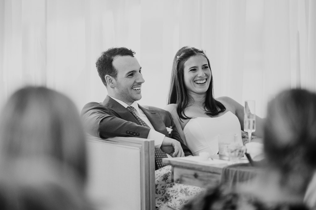 Black and white photo of newlyweds listening to a speech during their spring Être Farms wedding reception