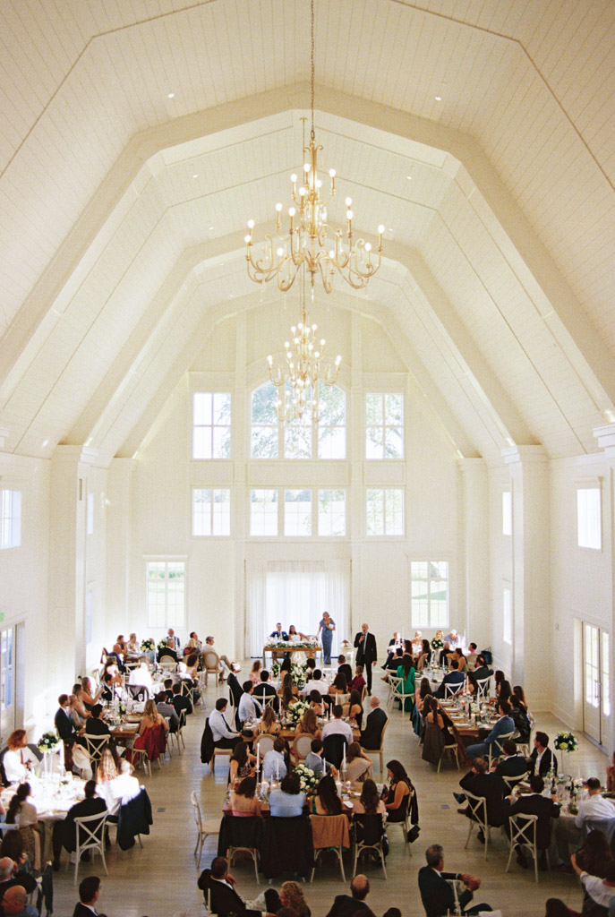 Être Farms bright wedding reception space with large windows and guests seated at decorated tables