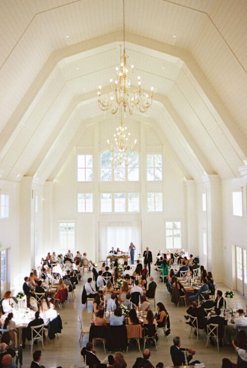 Être Farms bright wedding reception space with large windows and guests seated at decorated tables