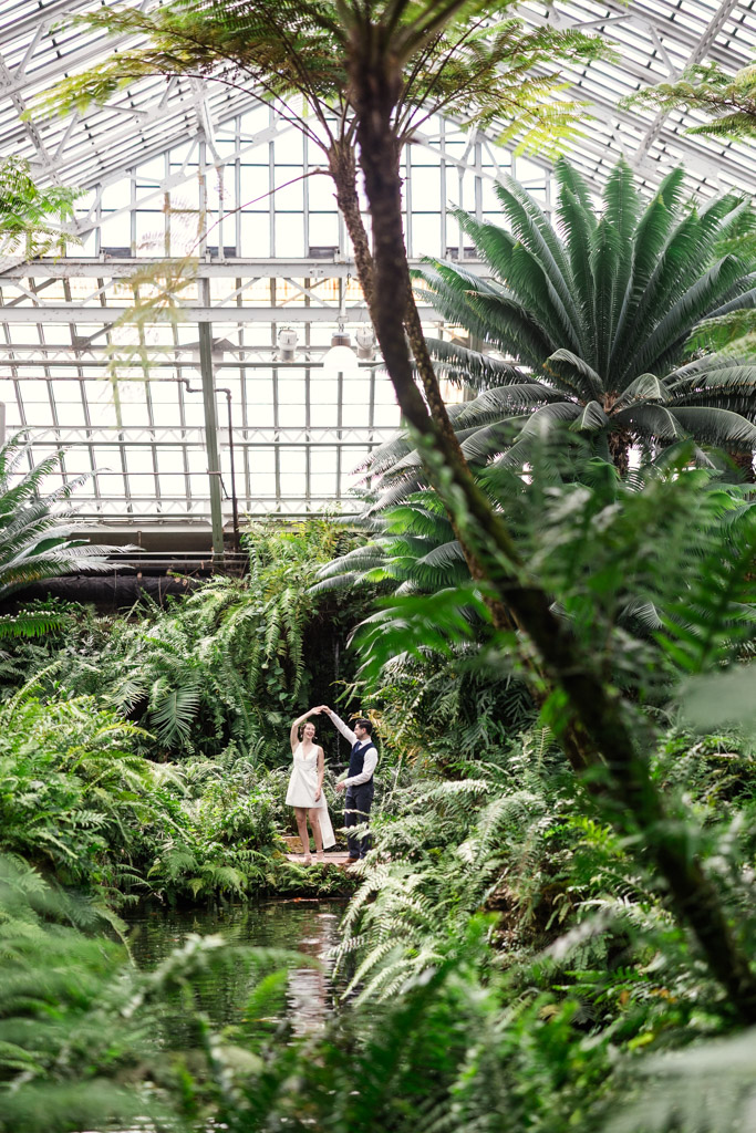 Engaged couple dances together inside the Fern Room filled with tropical plants at Garfield Park Conservatory in Chicago