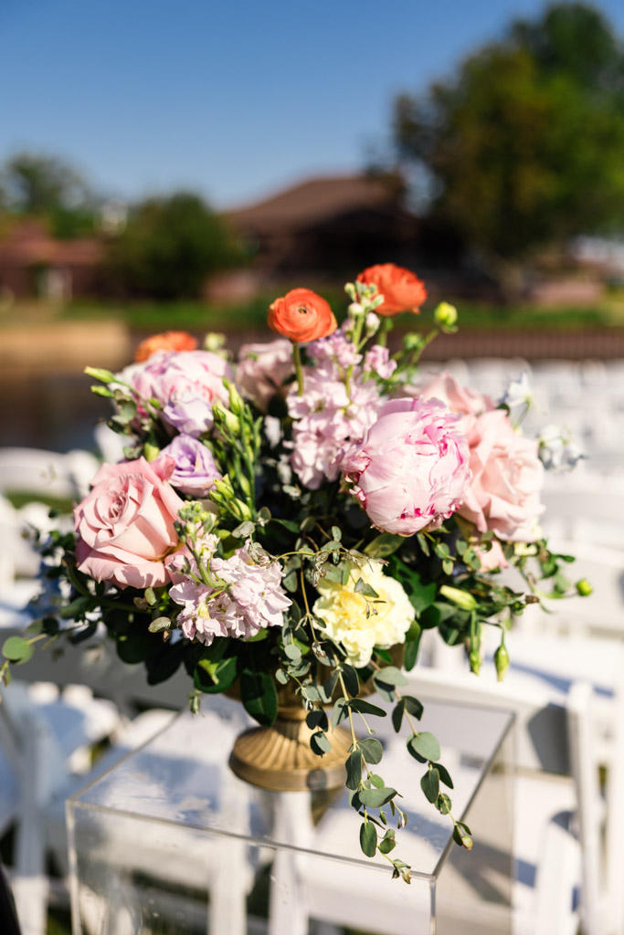 Bouquet of pink, purple, and orange flowers in a vase, set outdoors in the wedding ceremony space at Kemper Lakes Golf Club