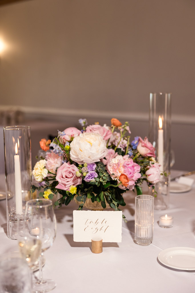 Floral centerpiece with pink and white flowers, candles, table marker on a white tablecloth for wedding reception at Kemper Lakes Golf Club