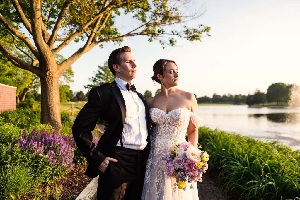 Bride and groom standing outdoors by a pond at Kemper Lakes Golf Club
