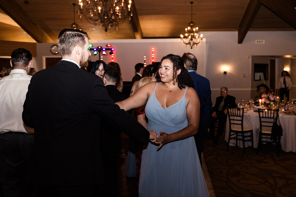 Maid of Honor in a blue dress smiles and dances with a man in a suit during wedding reception at Kemper Lakes Golf Club