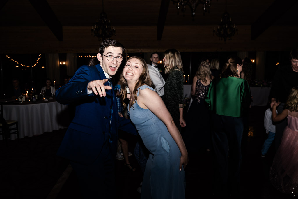 Guest in a suit and bridesmaid in a blue dress pose playfully on the dance floor during wedding reception at Kemper Lakes Golf Club