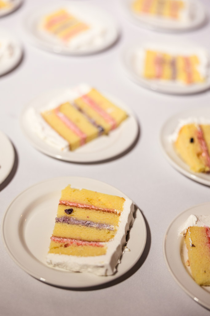 Slices of layered yellow cake with frosting on white plates, arranged on a table for Kemper Lakes Golf Club wedding reception