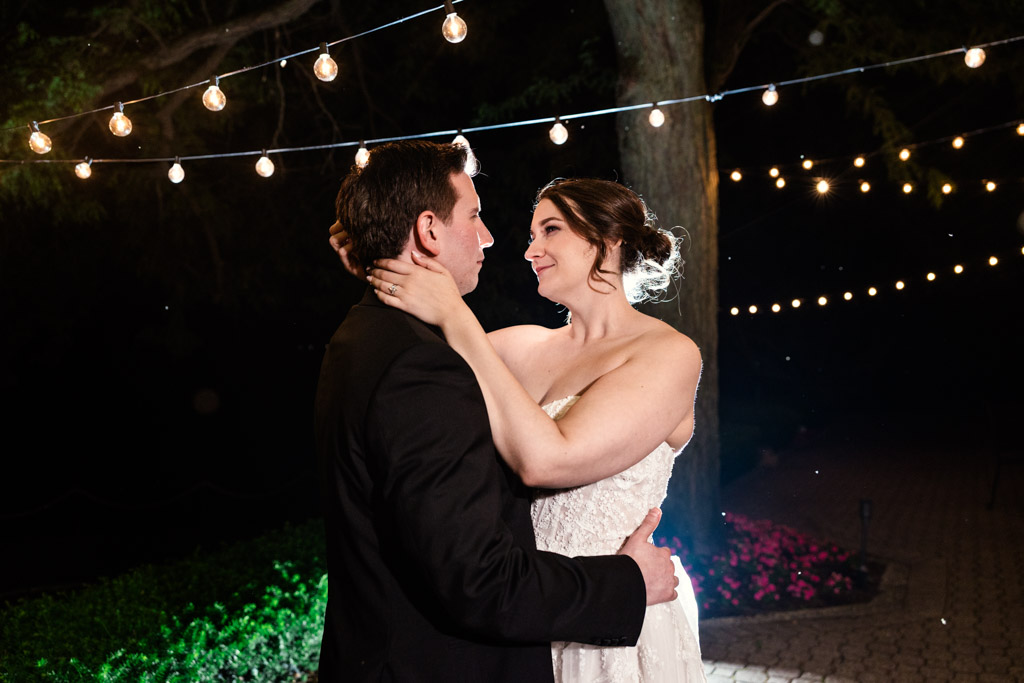 Romantic photo of bride and groom under string lights at night during their Kemper Lakes Golf Club wedding reception, gazing into each other’s eyes
