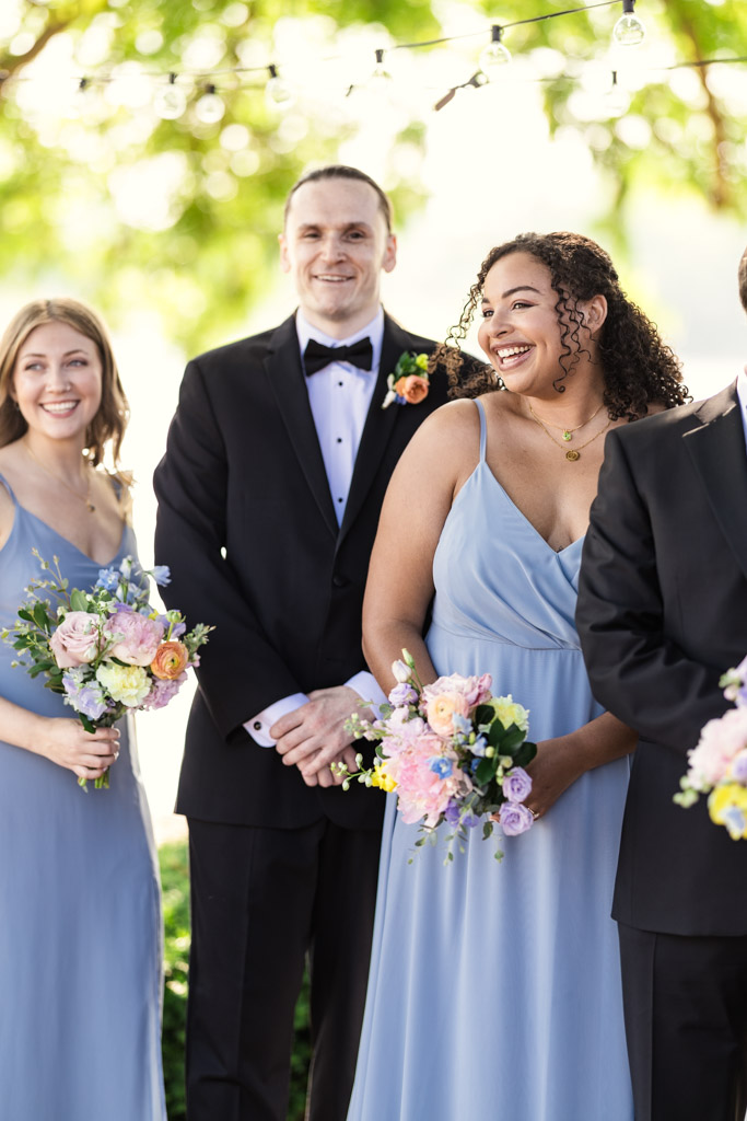 Maid of Honor and other wedding party members in formal wear, smiling and holding pastel flower bouquets outdoors during Kemper Lakes Golf Club wedding ceremony