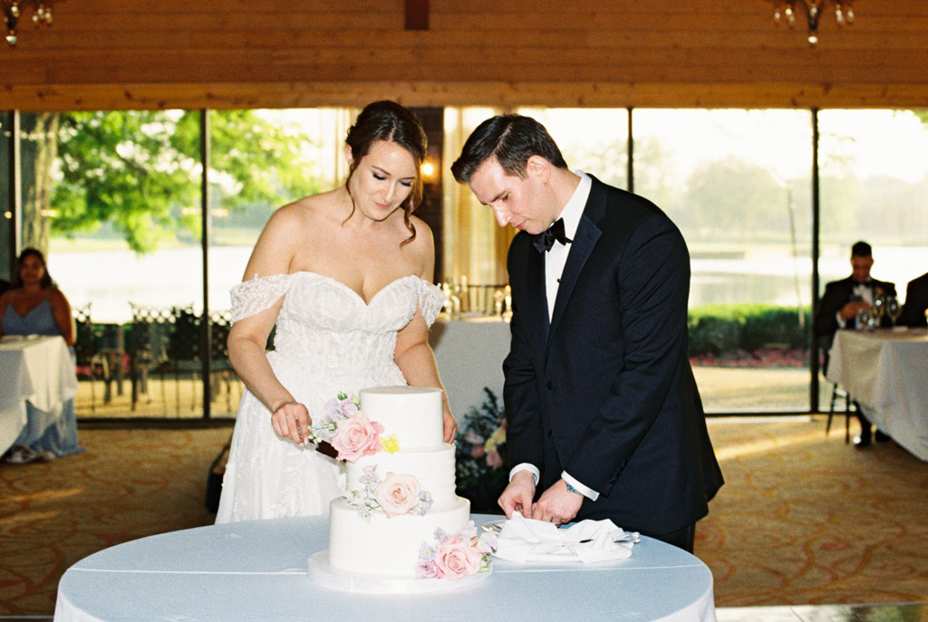 Film photo of bride and groom cutting their wedding cake together during reception at Kemper Lakes Golf Club