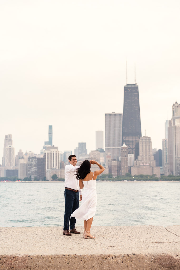 A couple dances by Lake Michigan at North Avenue Beach during Lincoln Park engagement session