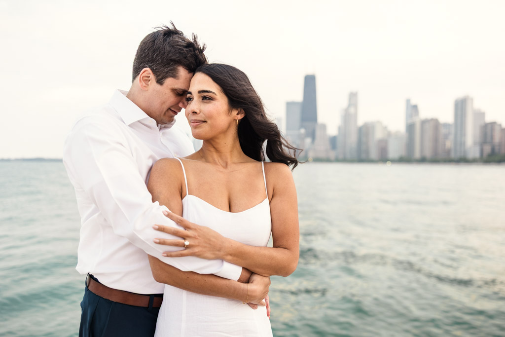 Couple embraces by the water at North Avenue Beach with Chicago skyline in the background