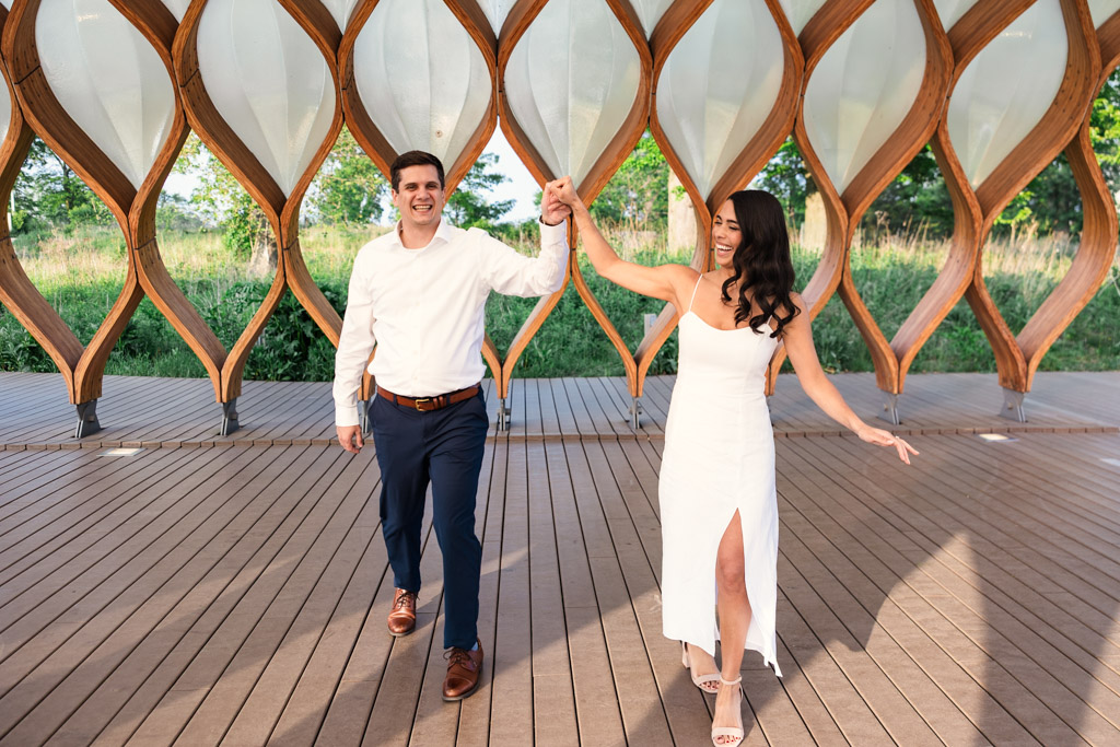 A couple smiles and dances under the Honeycomb pavilion in Lincoln Park during their spring engagement session