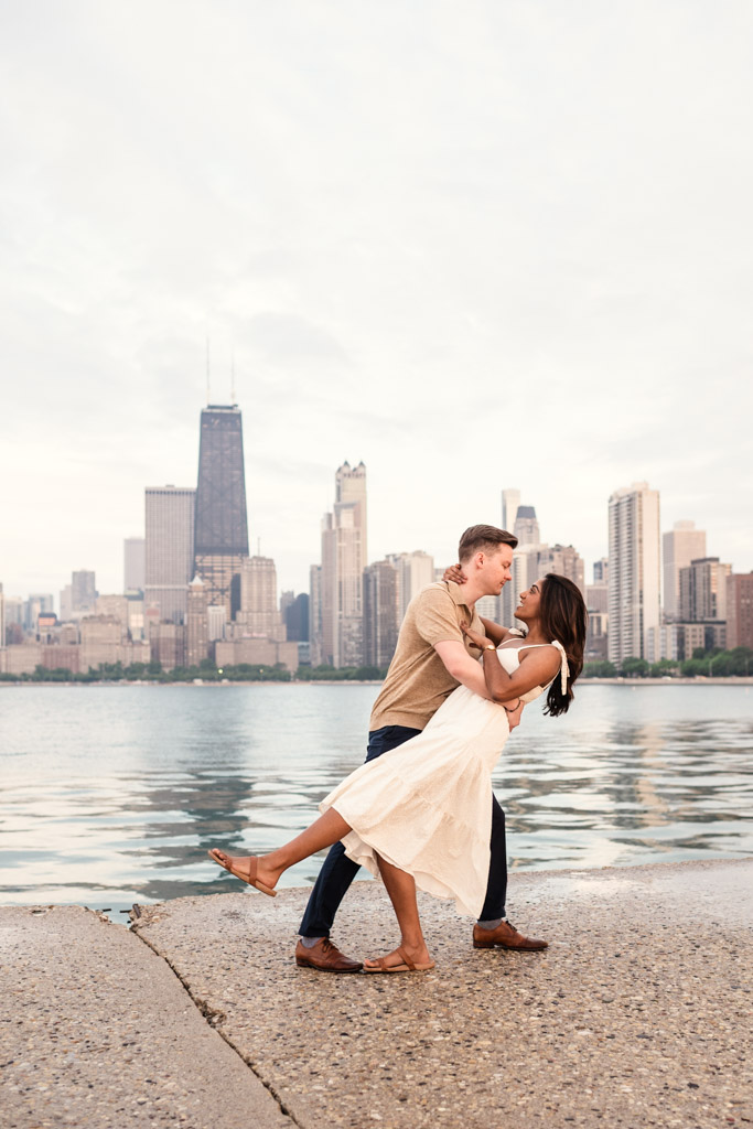 Man dips his partner on a Lake Michigan pier at North Avenue Beach with Chicago skyline in the background on a cloudy day,