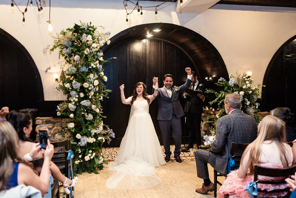 A newly married couple cheer after their indoor wedding ceremony at Osteria Via Stato