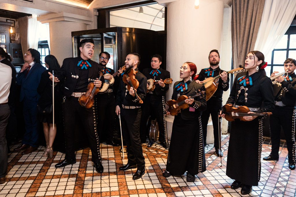 Mariachi EDC performs indoors at Osteria Via Stato, wearing black outfits with red and blue accents, playing string instruments