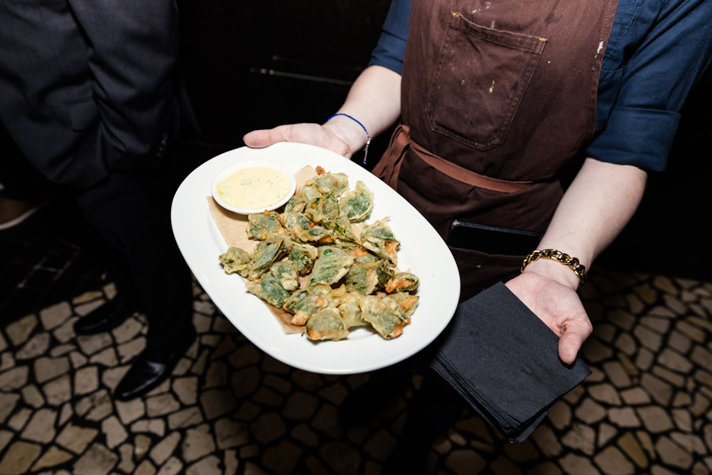A server at Osteria Via Stato holds a plate of appetizers