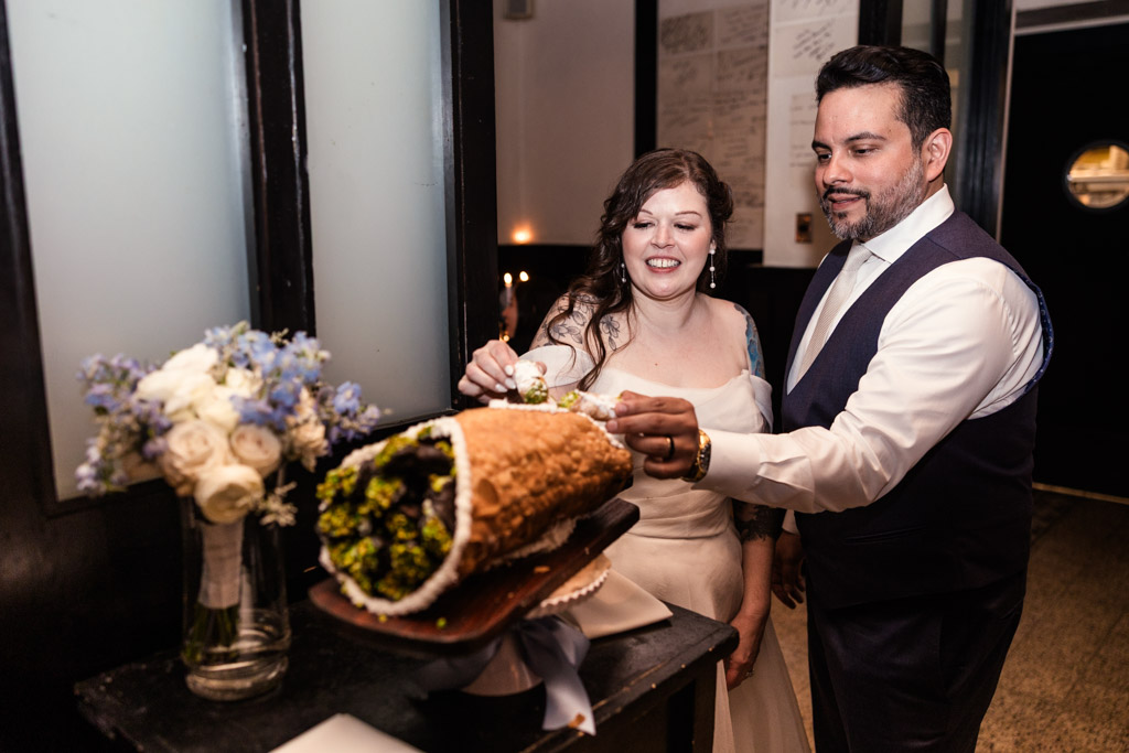 A bride and groom taste their wedding cannoli at Osteria Via Stato,