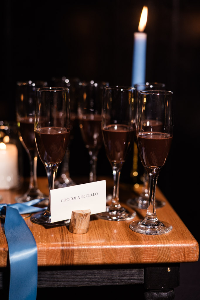 Glasses of chocolate liqueur on a wooden table with a lit blue candle for Osteria Via Stato wedding reception