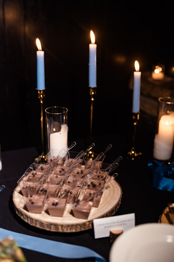 Chocolate desserts from Osteria Via Stato served in small cups on a wooden tray, with lit candles glowing softly in the background