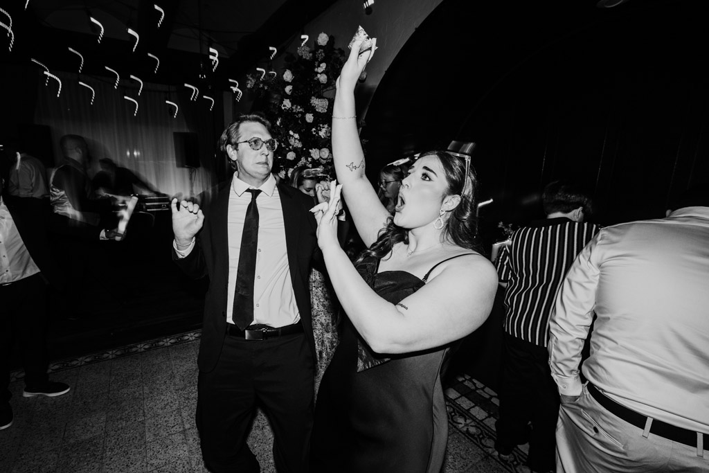 Black and whitephoto of woman and man dancing during wedding reception at Osteria Via Stato, surrounded by other guests in formal attire