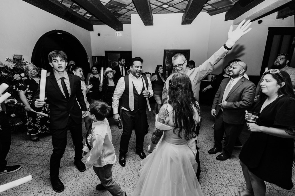Black and white photo of bride, groom and guests dance and celebrate together during wedding reception at Osteria Via Stato