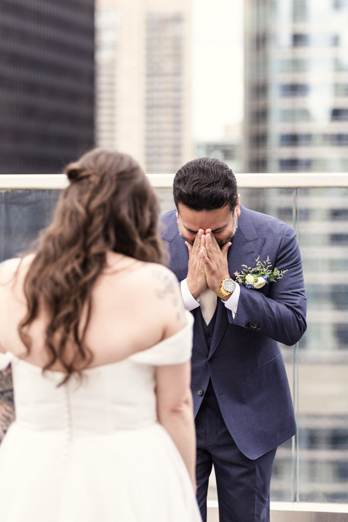 Emotional groom covers his face while seeing the bride during a rooftop wedding first look at Cerise in Virgin Hotels Chciago