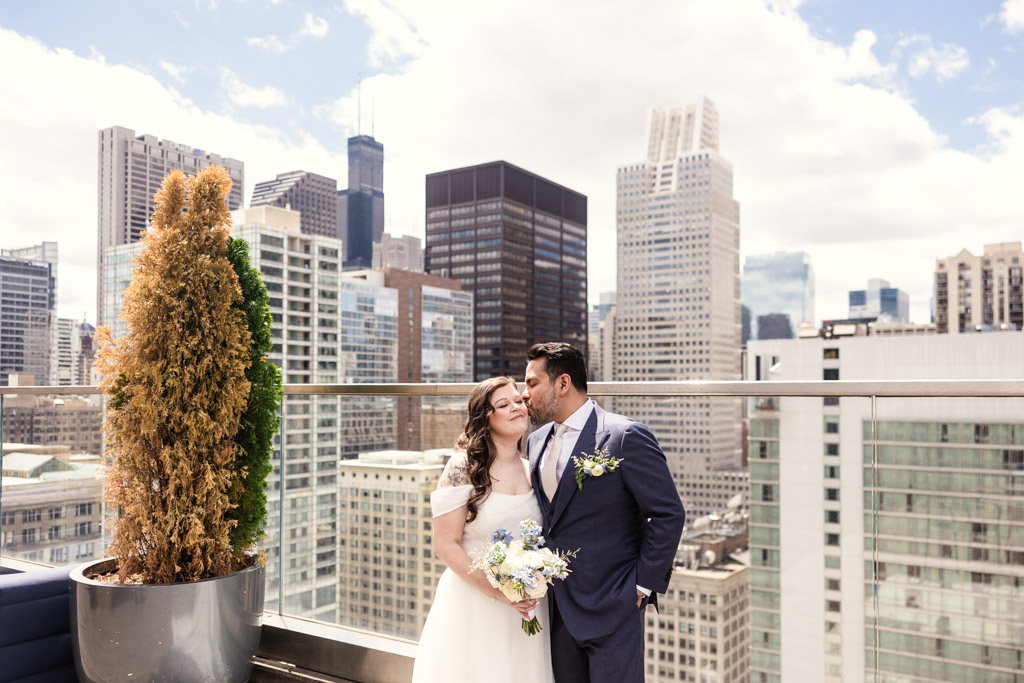 Bride and groom posing on the rooftop of Virgin Hotels Chicago with Chicago skyline in the background