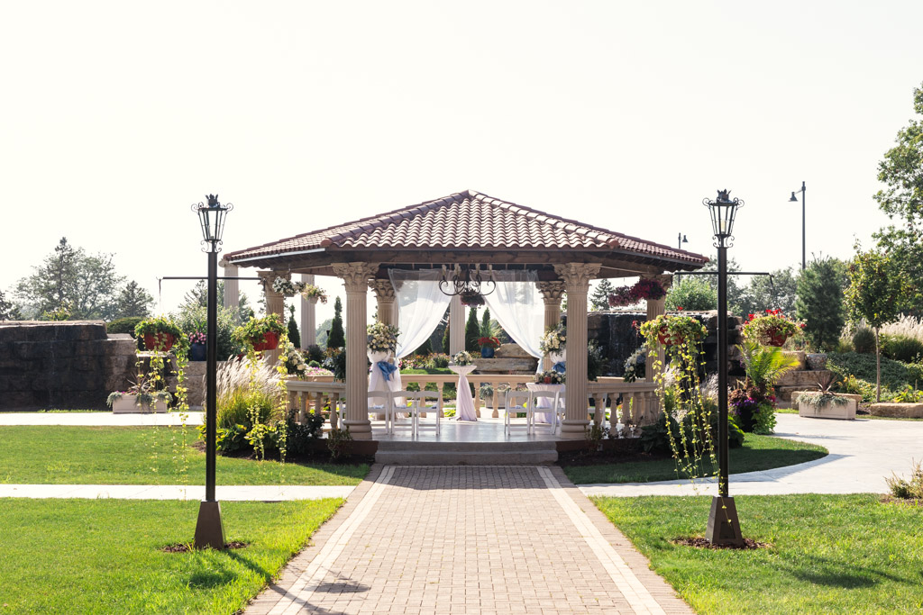 Gazebo at The Drake, decorated with flowers and white drapes, stands at the end of a brick path in a garden