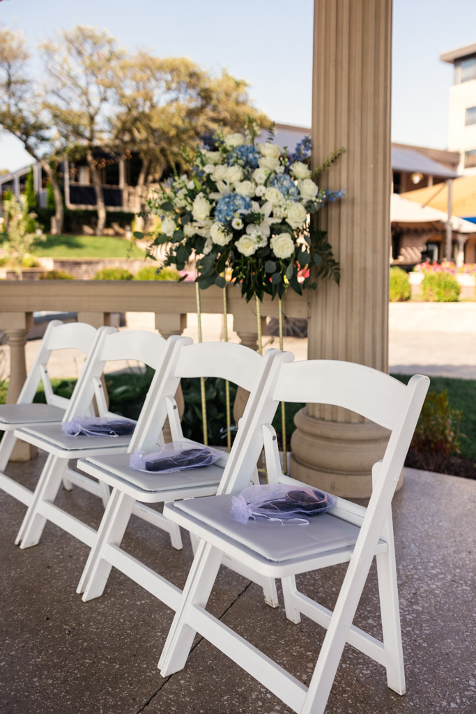 White chairs with gift bags on the seats and flower decor for wedding ceremony at The Drake Oak Brook