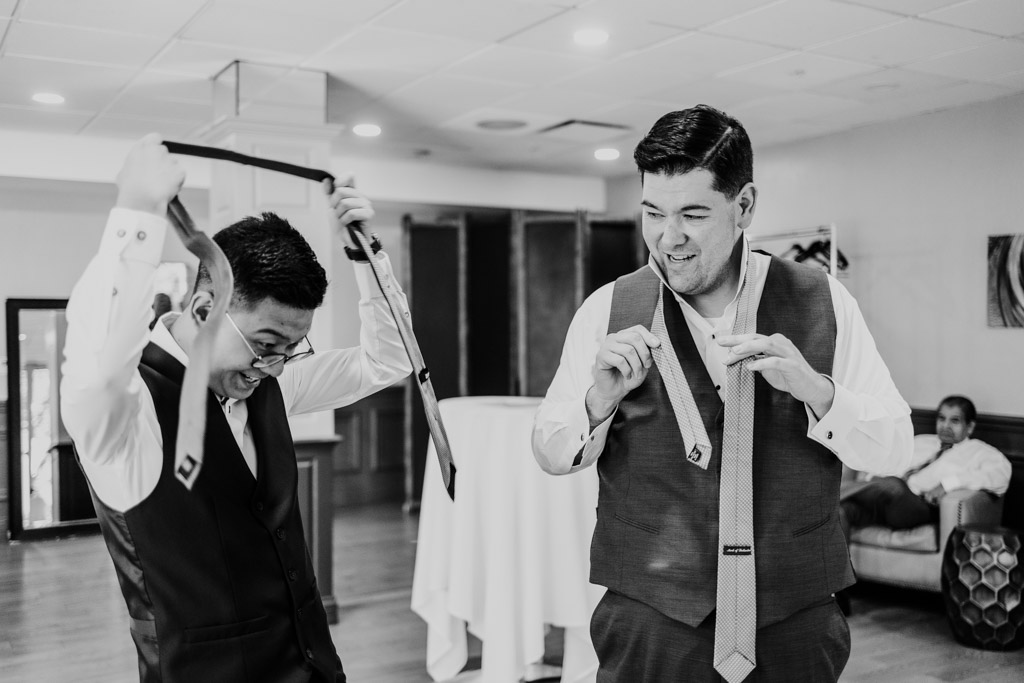 Black and white photo of two happy grooms getting ready in a room at The Drake Oak Brook