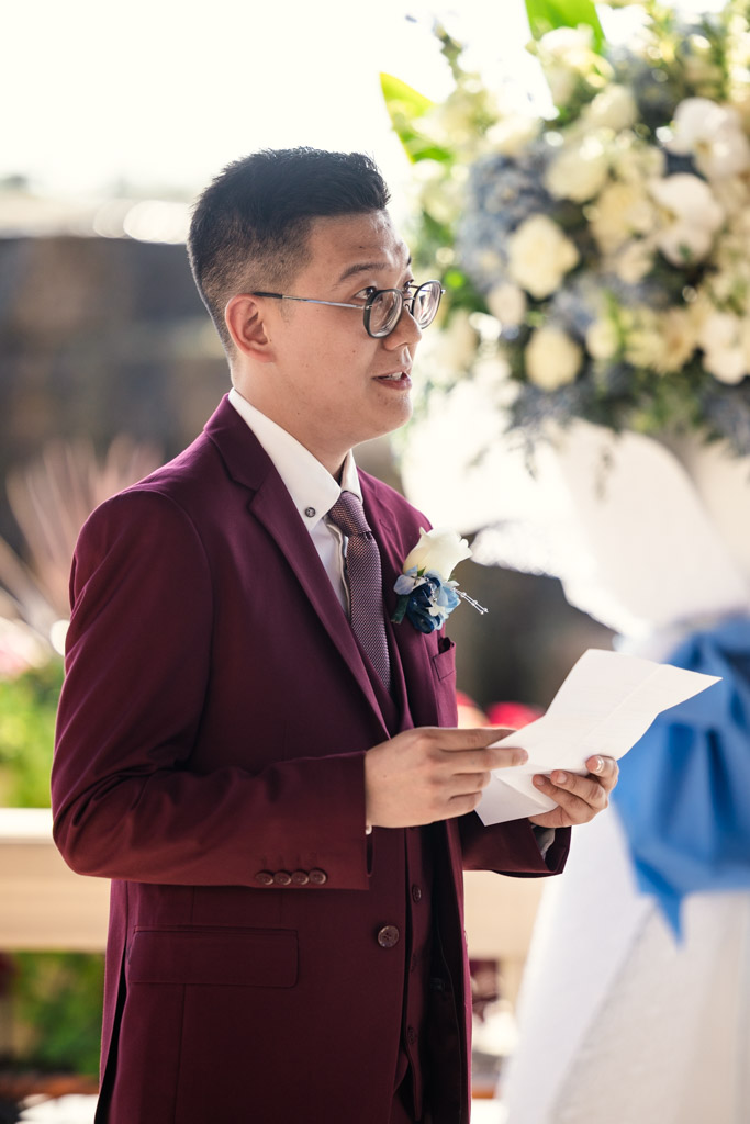Man in a burgundy suit reads his vows during elopement ceremony at The Drake in Oak Brook
