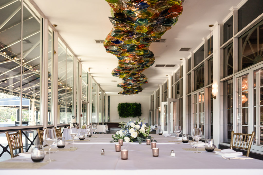 Wedding reception space at The Drake with a long table, floral centerpiece, glassware, and colorful ceiling art installation