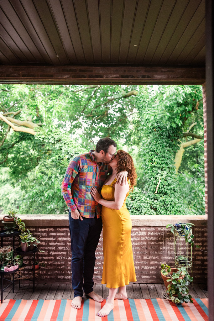 Engaged couple kisses on the brick porch of their home in Chicago's Ravenswood neighborhood
