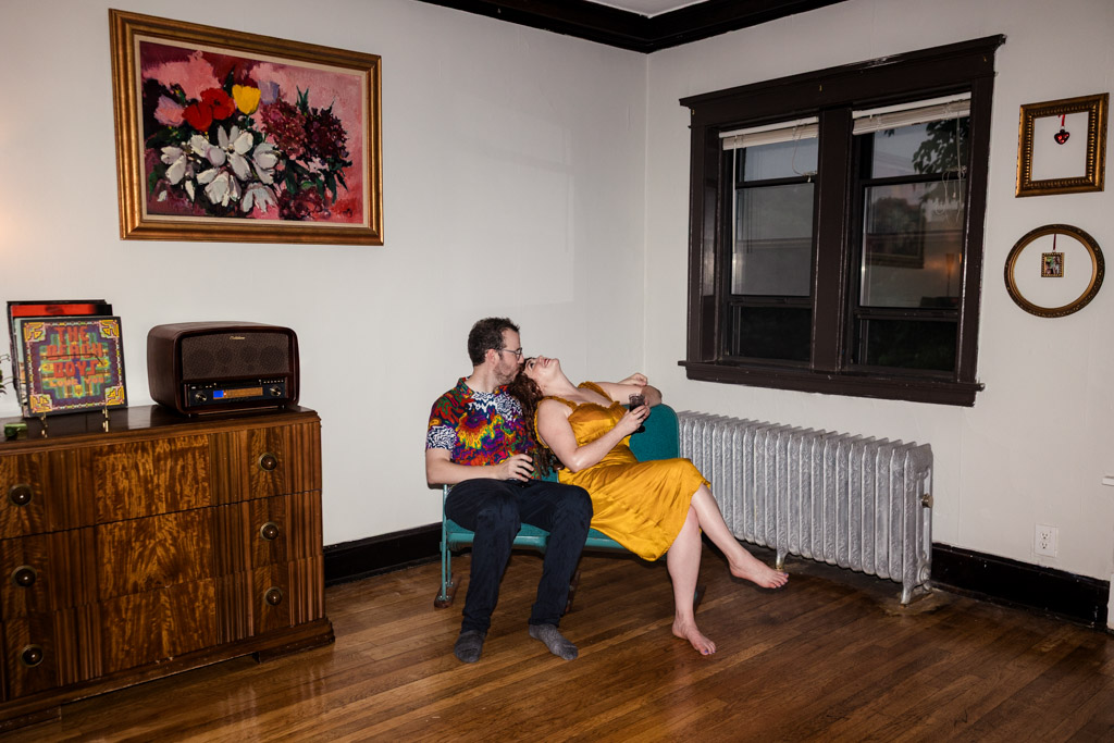 A couple sits on a small couch in their Ravenswood home during spring engagement session