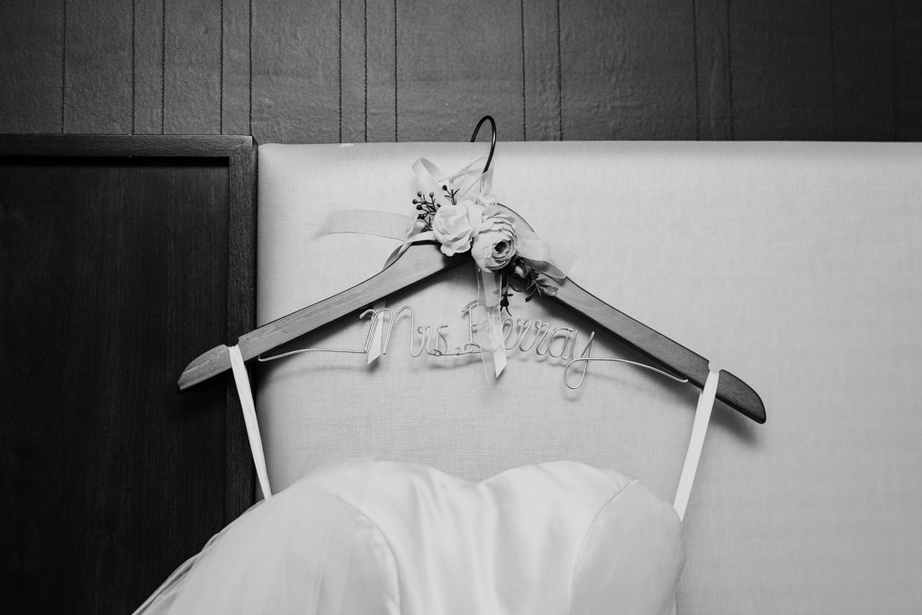 Black and white photo of bride's dress on custom hanger with floral decorations, for The Library at 190 wedding celebration in downtown Chicago