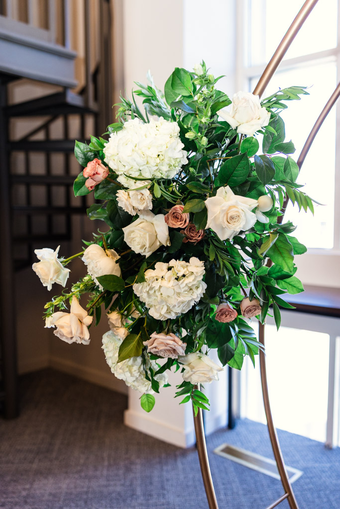 Detail photo of floral arrangement with white and blush roses, greenery, and hydrangeas decorating a gold arch at The Library at 190 in downtown Chicago