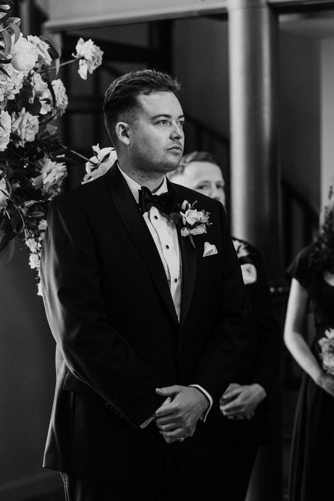 Black and white photo of groom waiting for bride during wedding ceremony at The Library at 190 in downtown Chicago
