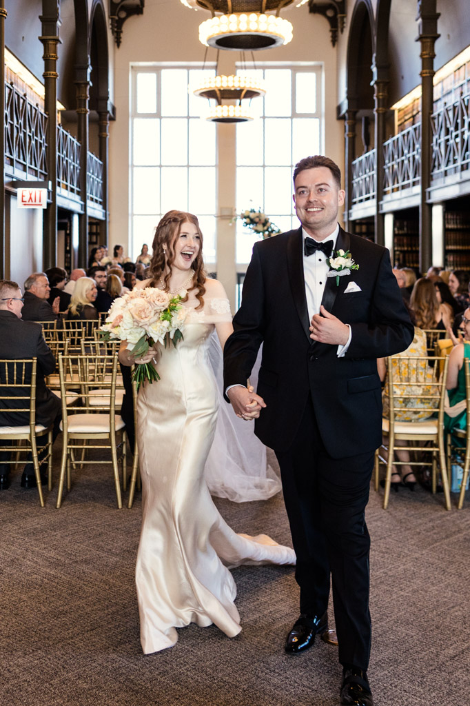 Happy newlyweds smiling and walking down the aisle together after their wedding ceremony iat The Library at 190 in downtown Chicago