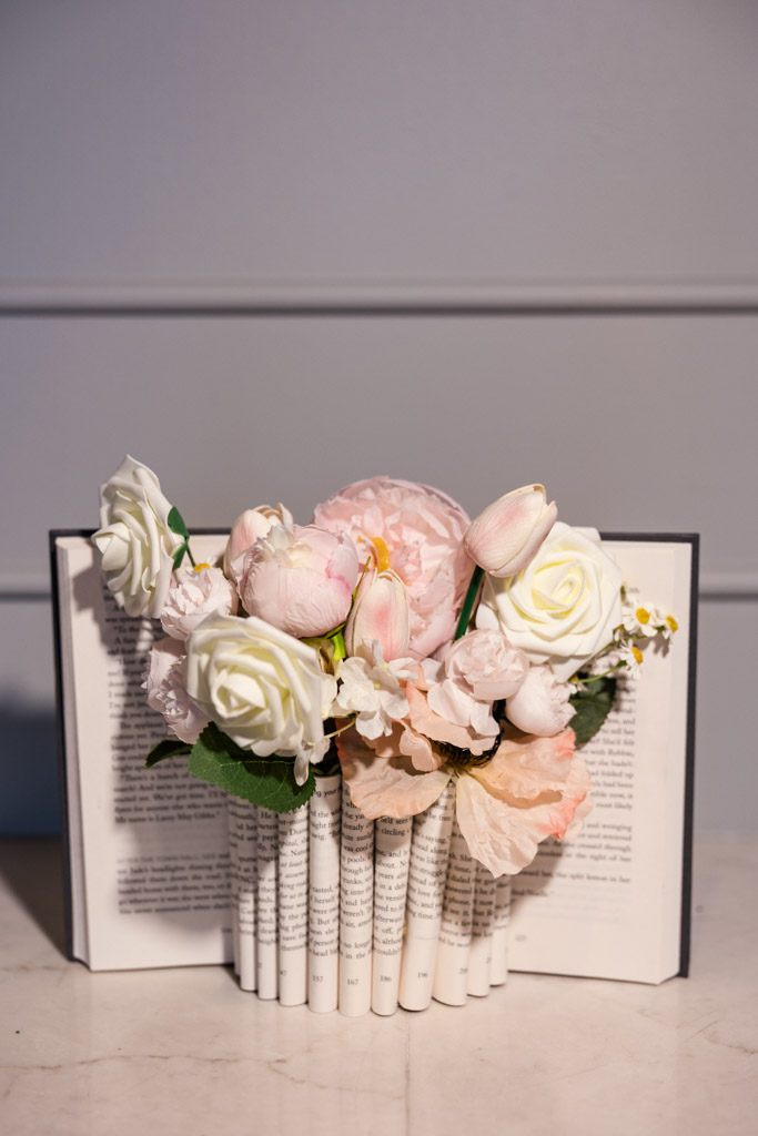 Custom decor piece with bouquet of pastel flowers arranged inside the curled pages of an open book on a marble surface for wedding celebration at The Library at 190 in downtown Chicago