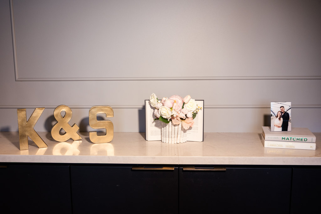 Gold K & S letters, a flower arrangement, stacked books, and a photo frame sit on a marble countertop for wedding celebration at The Library at 190 in downtown Chicago