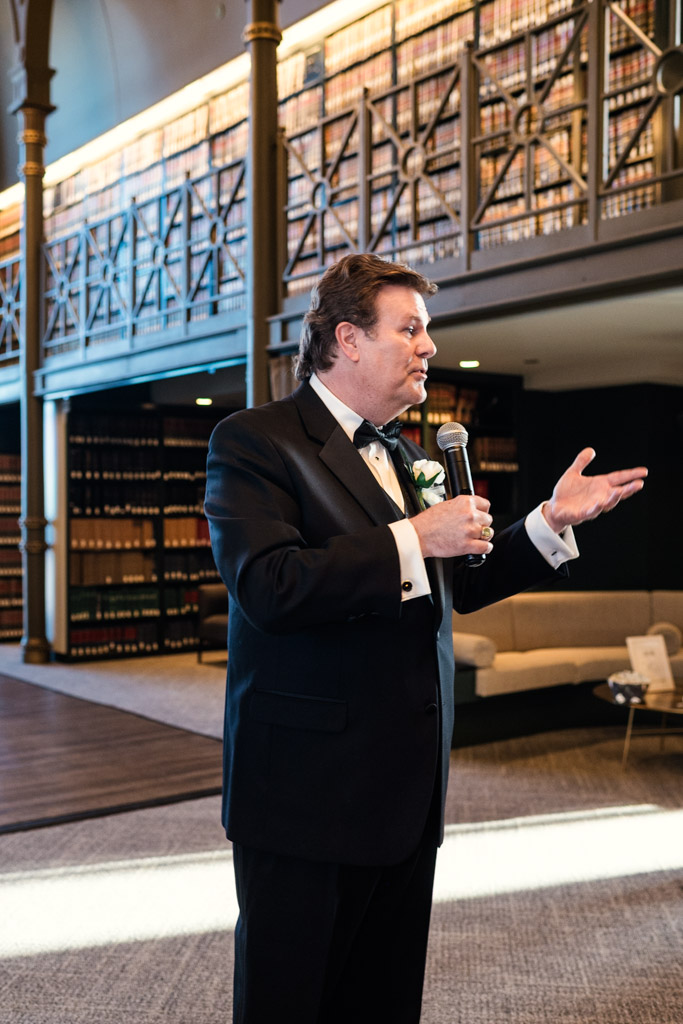 Father of the bride gives speech with bookshelves in the background during wedding reception at The Library at 190 in downtown Chicago