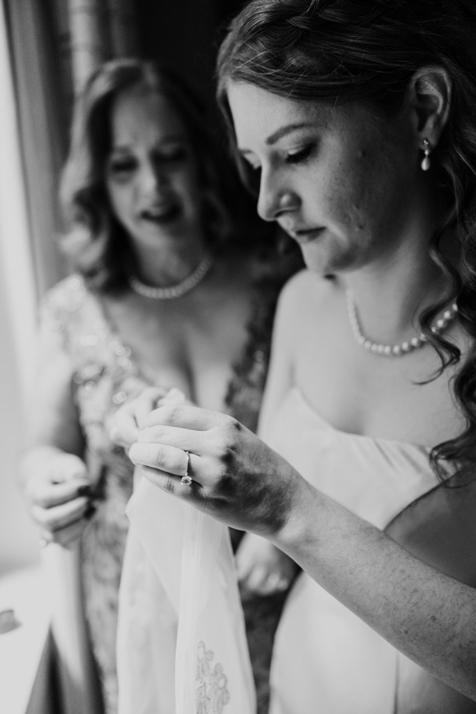 Black and white photo of bride examining her veil while her mother looks on before wedding celebration at The Library at 190 in downtown Chicago