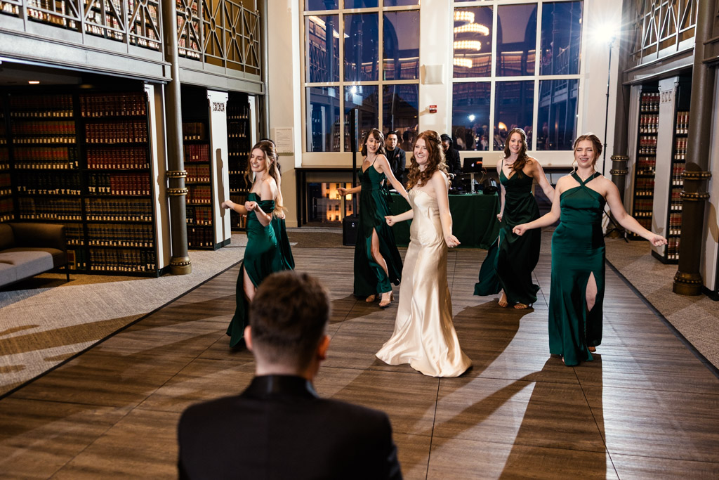Bride and bridesmaids in formal dresses perform a choreographed dance while groom watches during The Library at 190 wedding reception in downtown Chicago