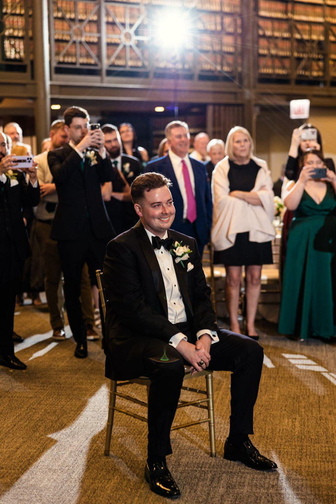 Groom in a tuxedo sits on a chair during wedding reception at The Library at 190 in downtown Chicago