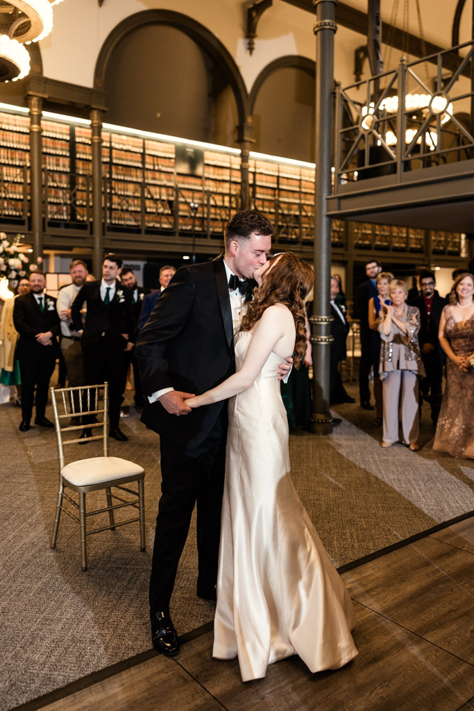 Bride and groom kiss while dancing at their The Library at 190 wedding reception, surrounded by guests