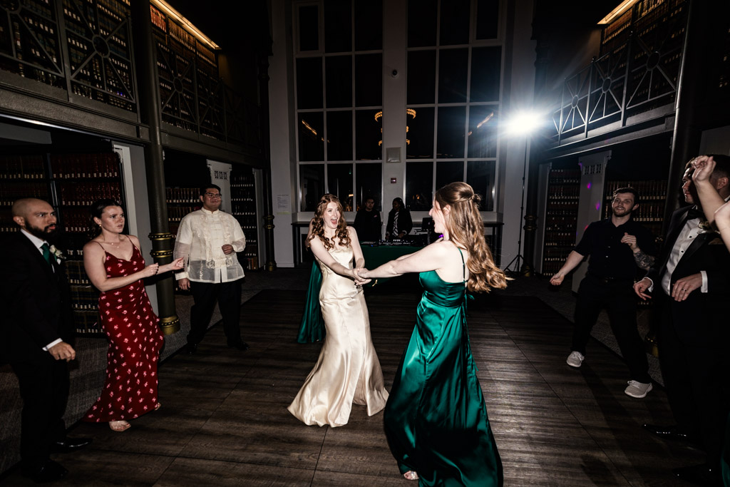 Bride and bridesmaid on the dance floor surrounded by guests during wedding reception at The Library at 190 in downtown Chicago